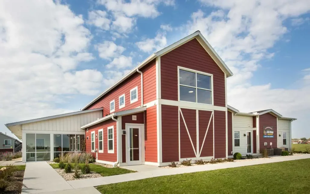 red and white school building that looks like a barn, blue sky with clouds