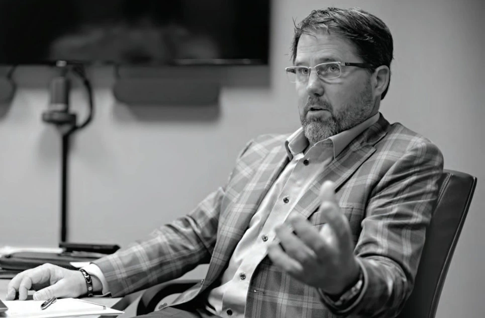 Black and white photo of Jeff Grundahl sitting at a table