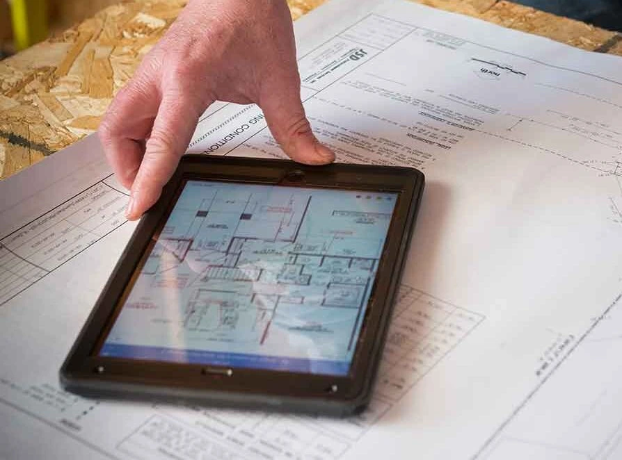 hand with tablet on top of building plans