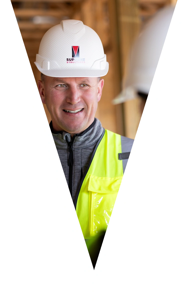 Man working at Supreme Structure safety vest smiling at a construction site