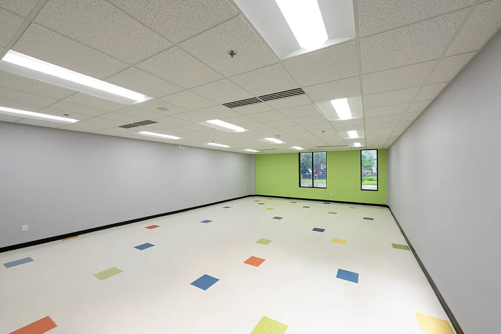Empty classroom. Bright green wall with windows, light gray walls, colorful tiled floor