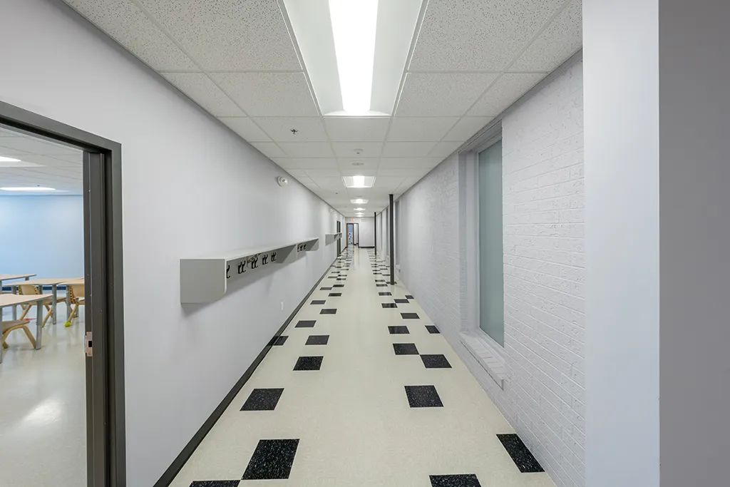 Long hallway with light gray walls, black and cream tiled floor