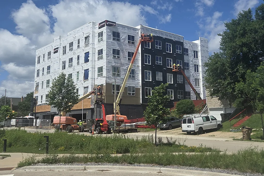 Exterior view of the Park Lofts apartment building under construction. Workers applying sections of siding.