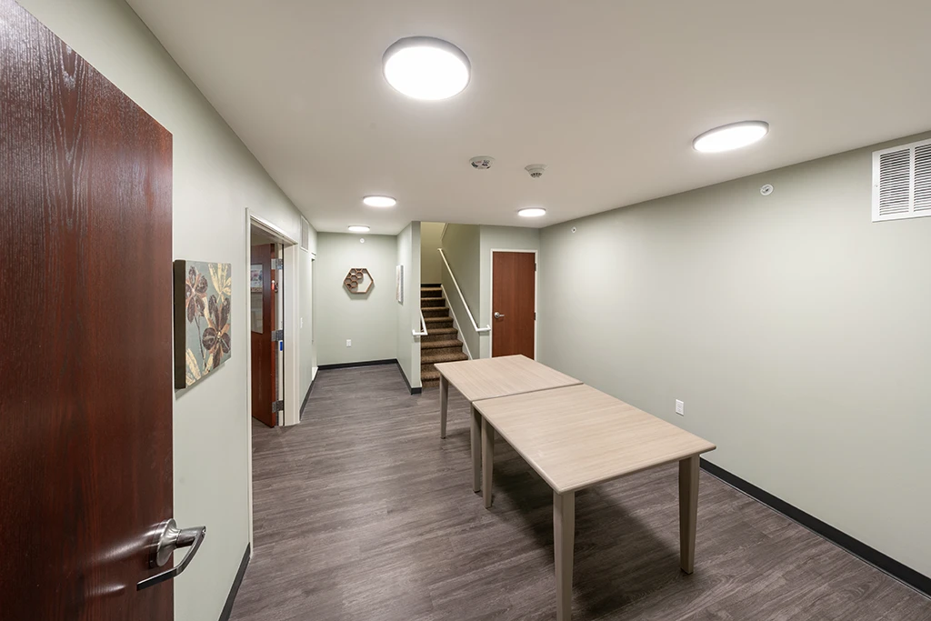 Room with tables, ceiling lights, brown doors and staircase
