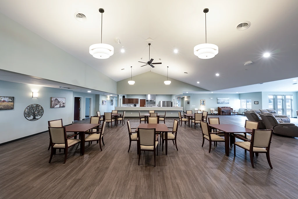 Large open room with small tables and groups of chairs with kitchen behind