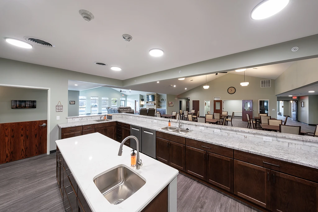 Open kitchen area with counters, brown cabinets, sink, stove and island