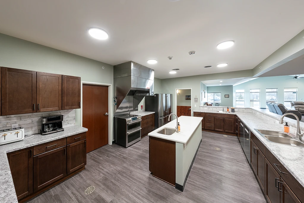 Open kitchen area with counters, brown cabinets, sink, stove and island