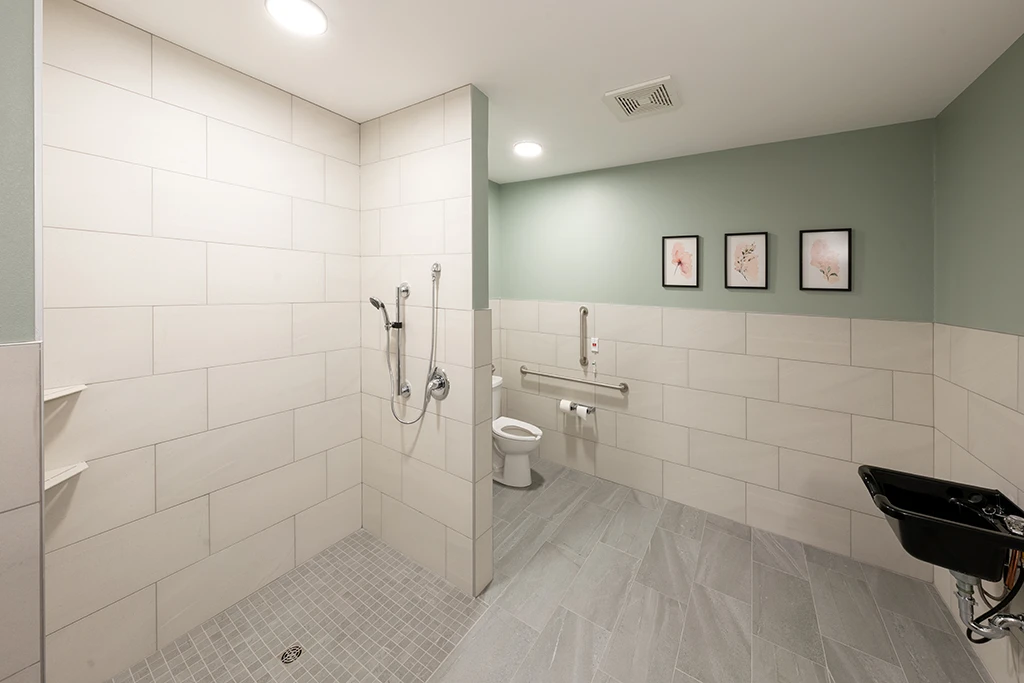 Large open bathroom with tile, roll-in shower, toilet, and sink