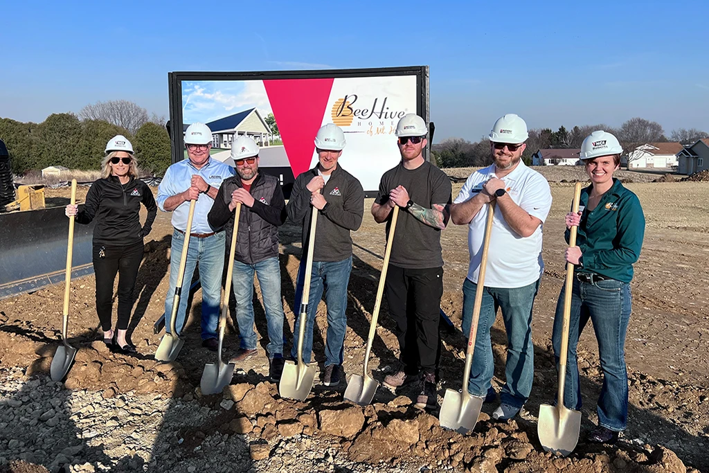 7 people holding shovels and wearing hard hats
