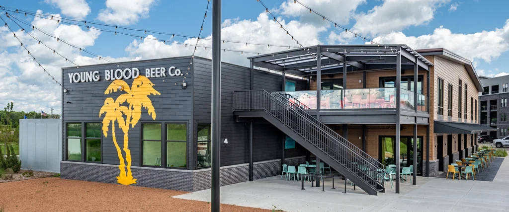 Exterior view of restaurant with brown siding, attached brewery with dark gray siding, and a staircase to an outdoor dining area
