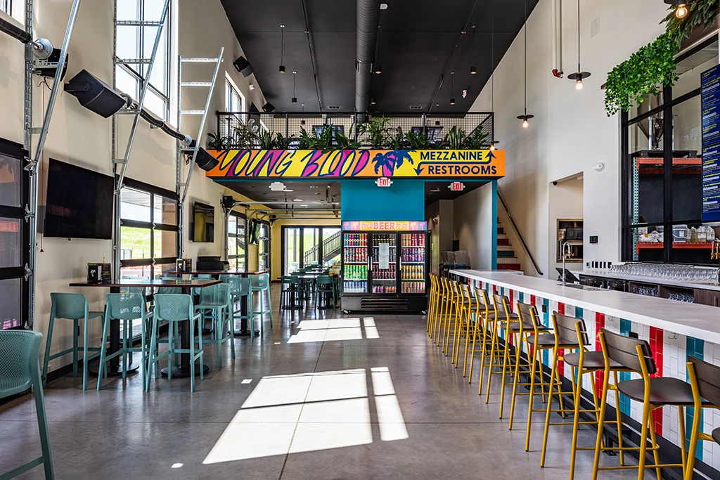 Large room with bar at right, individual tables at left, and mezzanine straight ahead