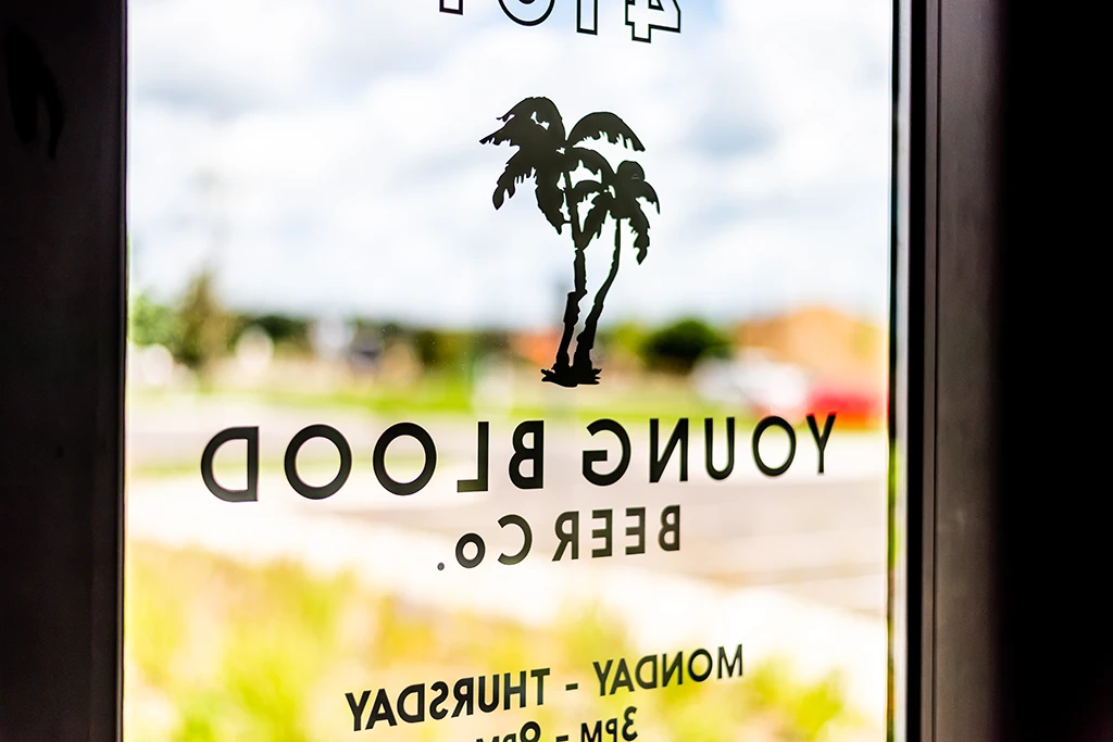 View through glass door with Young Blood Beer Co signage reversed in black