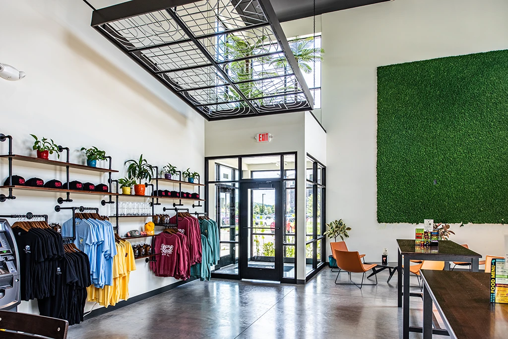 Room with white walls, black glass door, merchandise on wall and large green grassy panel on wall