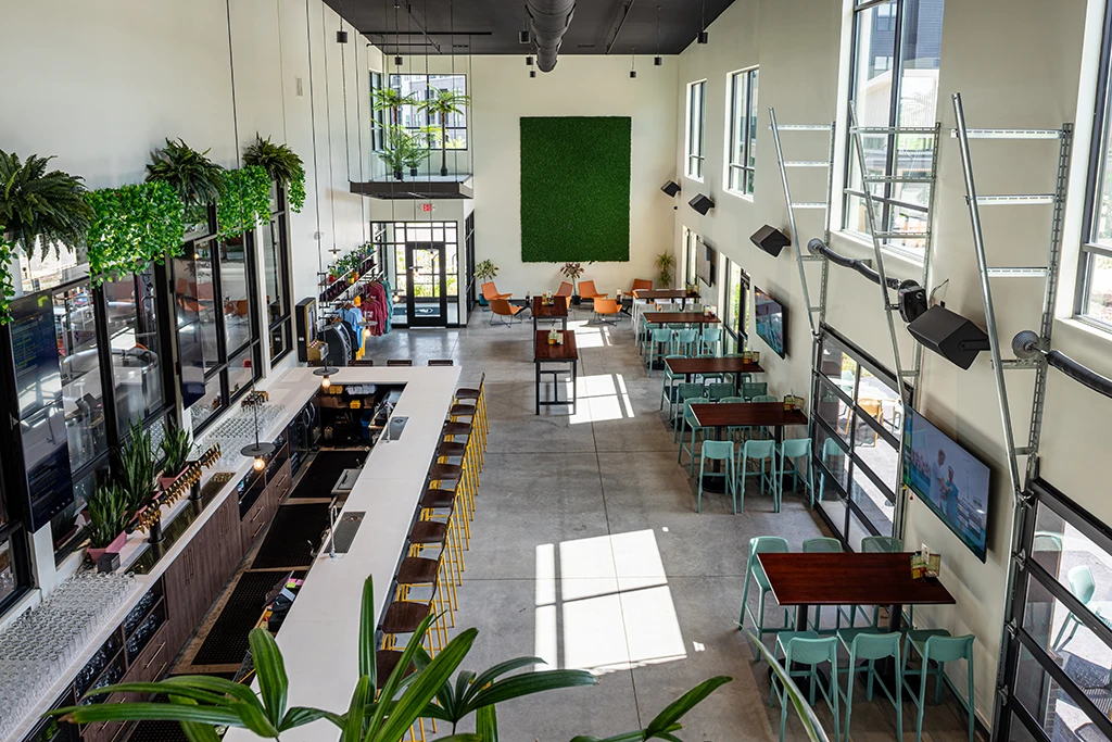View of dining area from mezzanine with large windows, white walls, bar and groups of tables and chairs