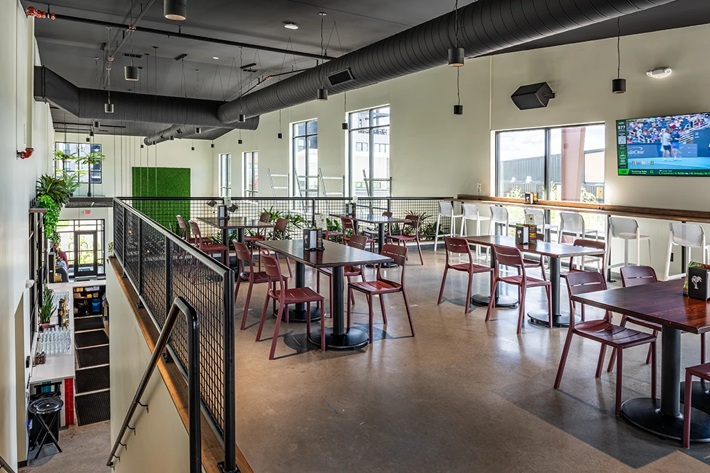 Mezzanine area with tables and chairs, white walls, windows and black ceiling